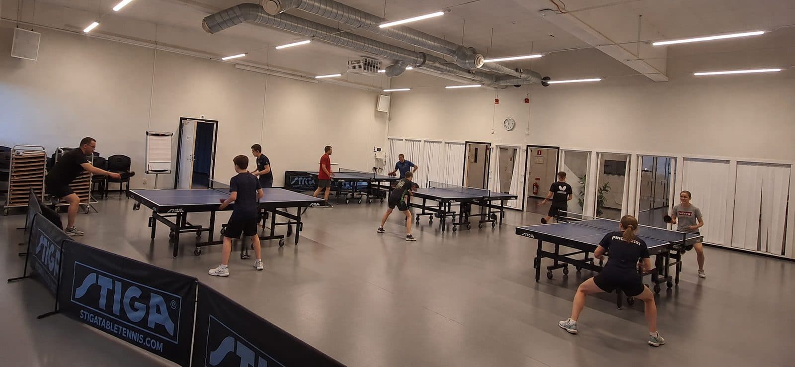 Lilla Manschetten — bordtennishall med flera bord, spelare tränar