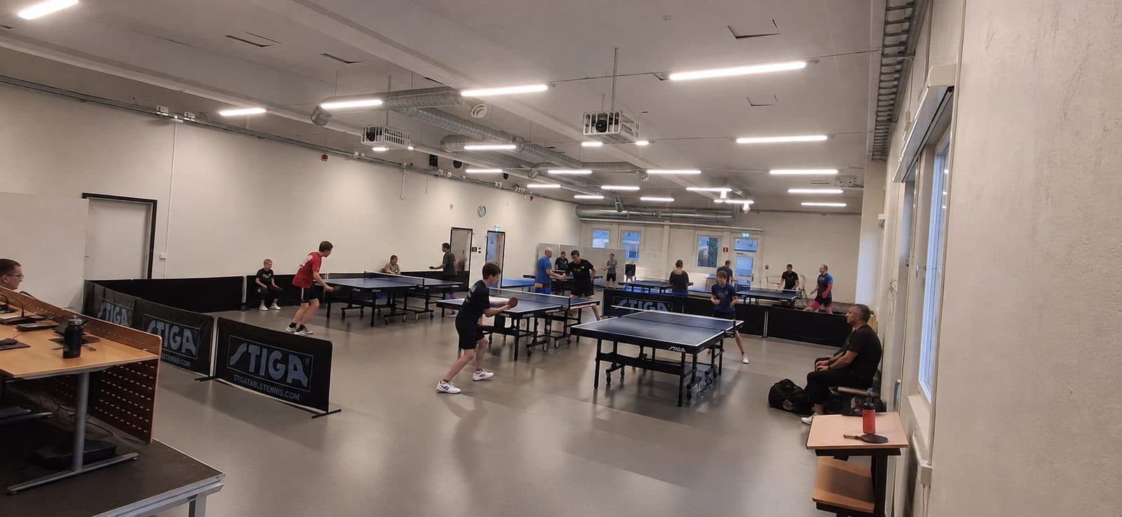 Stora Manschetten — bordtennishall med flera bord, spelare tränar